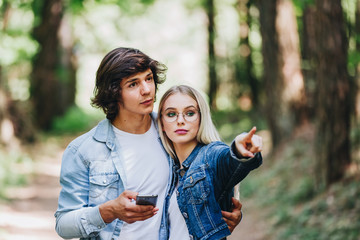 Obraz premium Young couple on adventure in forest using GPS on smartphone as orientation