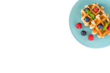 Traditional belgian waffles with blueberries and raspberries, isolated on white background. Top view. Copyspace
