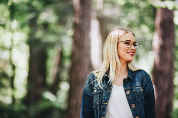 Portrait of young blond woman who posing while standing in forest