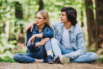 Romantic young couple sitting together in forest and enjoying sunny day together