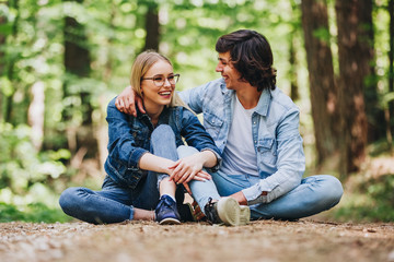 Romantic young couple sitting together in forest and enjoying sunny day together