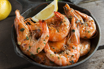 fried roasted shrimps in frying pan with lemon greens parsley garlic