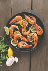 fried roasted shrimps in frying pan with lemon greens parsley garlic