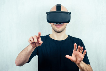 portrait of a young handsome bald man in a virtual reality mask (glasses) points his finger. the...