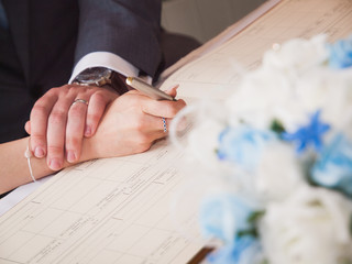 Young couple signing wedding register documents. Focus on hand