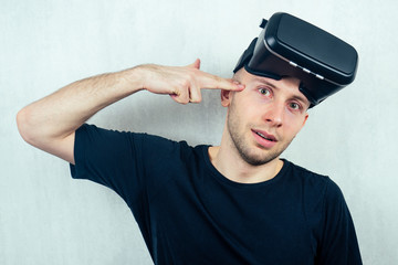 Naklejka premium portrait of a young handsome bald man in a mask (glasses) of virtual reality points with his finger. the concept of video games and reality copyspace