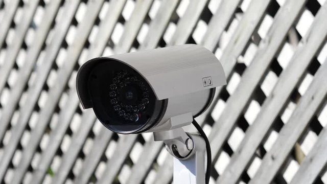 Security camera moving panning and tilting recording what's happening outside a building. Motorized CCTV surveillance.