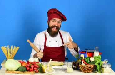 Chef with pasta, vegetables and dough on table.