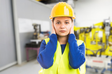 Young female engineer covering her ears.