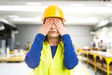Young female engineer covering her eyes.