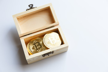 Golden bitcoin coins in a small wood box.