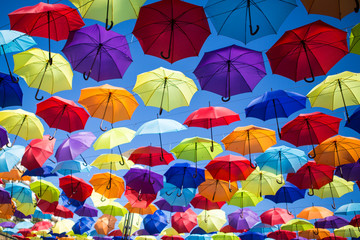 Fototapeta na wymiar Colorful umbrellas background. Coloruful umbrellas urban street decoration. Hanging Multicoloured umbrellas over blue sky. umbrellas with many colours.