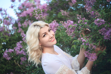 Fototapeta premium Beautiful woman in a spring garden with blooming lilacs.