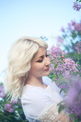 Beautiful woman in a spring garden with blooming lilacs.