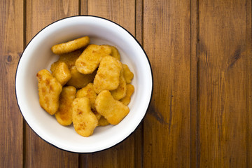 Appetizing, bright and beautiful chicken nuggets in an iron bowl and copy space