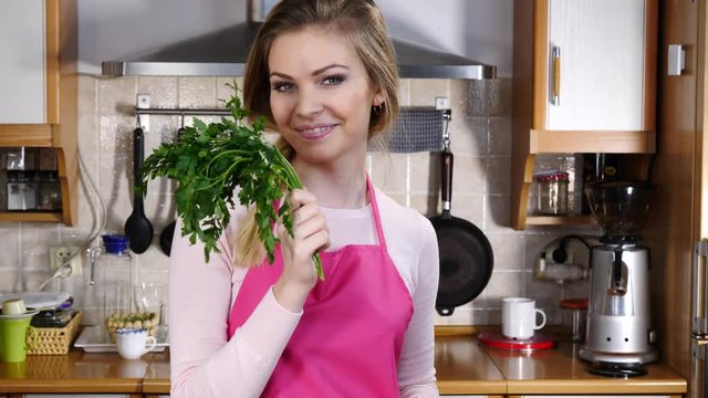 Pretty young adult woman holding green parsley seasoning herb vegetable. Healthy food smell concept.