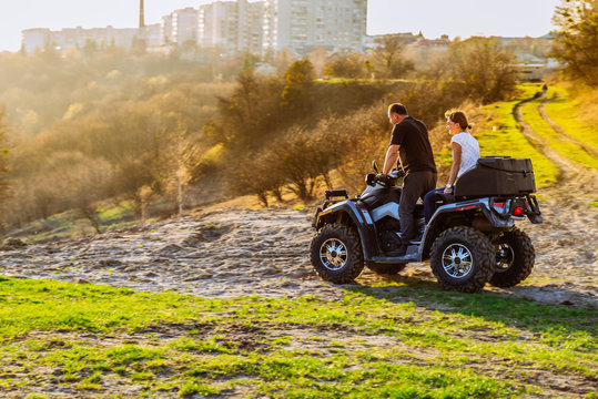 couple enjoys riding an ATV on forest hills on sunset