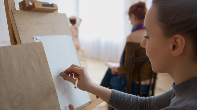 Young female painter draws sketches in drawing studio