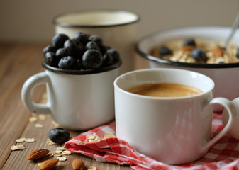 A healthy breakfast is a great start to a new day. Oatmeal porridge, coffee, berries and nuts on a wooden table.