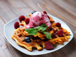 Plate of belgian waffles with ice cream and fresh berries - raspberries and blueberries.top view