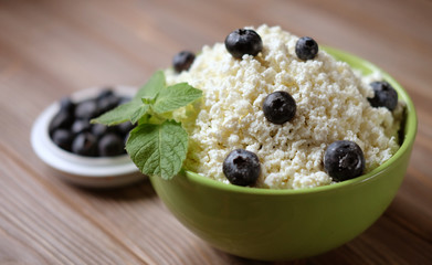 Cottage cheese and blueberry in a bowl on a table. Good breakfast