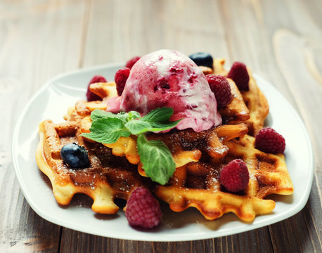 Plate of belgian waffles with ice cream and fresh berries - raspberries and blueberries. top view