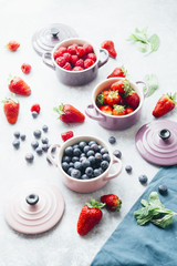 Summer fruit background, top view of berries , smoothie ingredient, inside ceramic colored cocotte, blueberries, strawberries, raspberries, flat lay