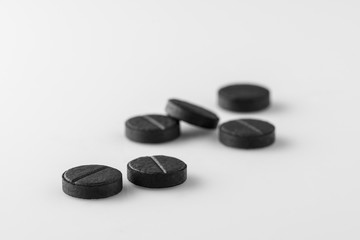 several black medical activated charcoal pills on white background. Isolated