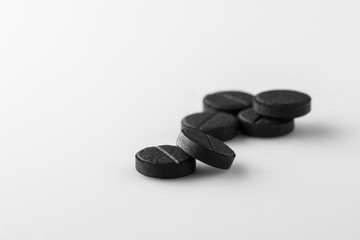 several black medical activated charcoal pills on white background. Isolated