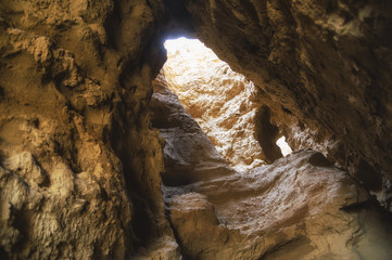 Hole with a gleam in a small rocky cave