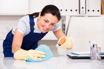 Portrait of adult female cleaning office table