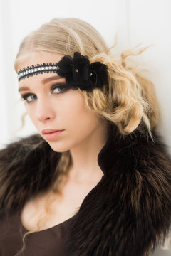 Closeup portrait of blond actress playing in 1920s movie. Pretty girl in headband and fur collar isolated in white background