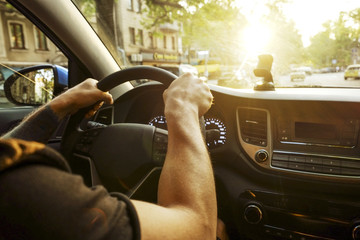 Young man in black t-shirt holding steering wheel, driving car, forearm tattoo, hands close up....
