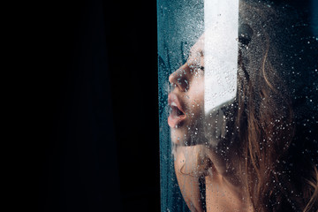Shower and hygiene spa treatment. Window with water drops before girl with makeup. Sexy woman behind plastic sheet with water drops. Fashion and beauty. Rain drops on window glass with face of girl