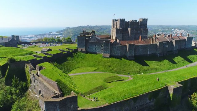 Aerial view of medieval Dover Castle on hill in spring, cityscape of Dover on background, clear blue sky - England, United Kingdom from above, 4k UHD