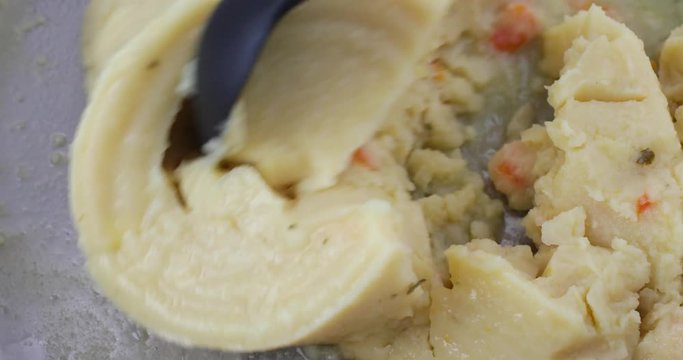 A very close video of stirring canned potato soup in a pan while heating.