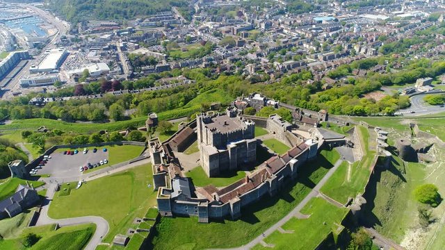 Aerial view of medieval Dover Castle on hill in spring, cityscape of Dover on background, clear blue sky - England, United Kingdom from above, 4k UHD