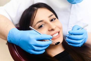 Fototapeta premium Young male dentist working in dental clinic with female patient in the chair