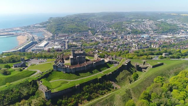 Aerial view of medieval Dover Castle on hill in spring, cityscape of Dover on background, clear blue sky - England, United Kingdom from above, 4k UHD