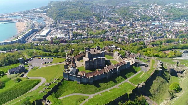 Aerial view of medieval Dover Castle on hill in spring, cityscape of Dover on background, clear blue sky - England, United Kingdom from above, 4k UHD
