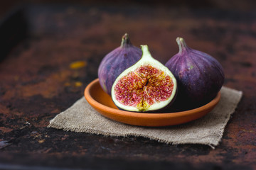 Fig fruits on clay plate on dark background.