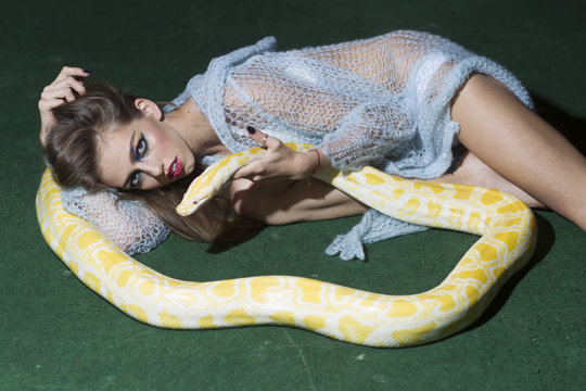 Beautiful woman brunette holding python snake, temptation