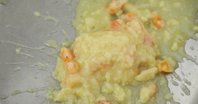 A very close video of dumping a can of potato soup into a pan for heating.