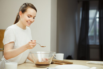 Obraz na płótnie Canvas Woman holding spoon over glass bowl, preparation of sweet dessert