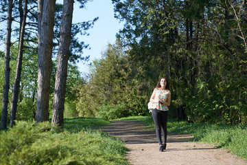 young girl walking in spring forest with camera and taking pictures