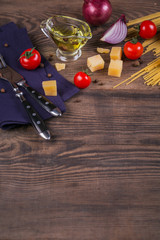 Ingredients for cooking spaghetti - raw pasta, tomato, olive oil, spices, herbs