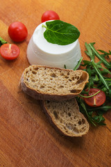 ricotta cheese with arugula and tomatoes cherry.crunchy baguette slices with cream cheese and green arugula on wooden  board