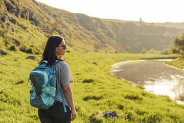 Naklejka premium Traveler Woman with backpack looking landscape view at nature green field at sunset, tourism concept