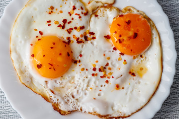 Fried eggs on a plate with chili peper.