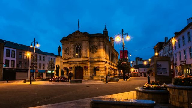 Coleraine, North Ireland. View of Town Hall in Coleraine, North Ireland, UK at sunset. Time-lapse at night with closed shops and cafes. Illuminated town hall with cloudy blue sky
